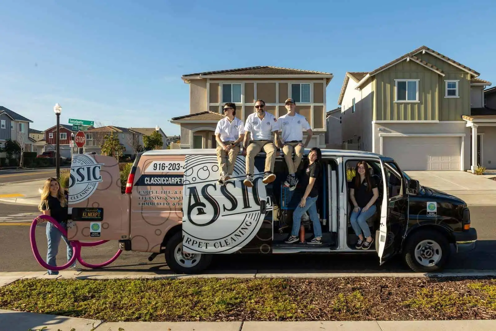 The Classic Carpet Cleaning team standing on their branded service van in a Roseville neighborhood