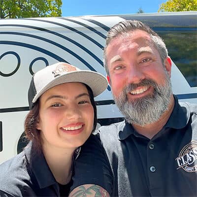 Two Classic Carpet Cleaning team members smiling in front of the van