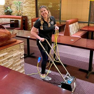 Technician cleaning carpet in a commercial dining room